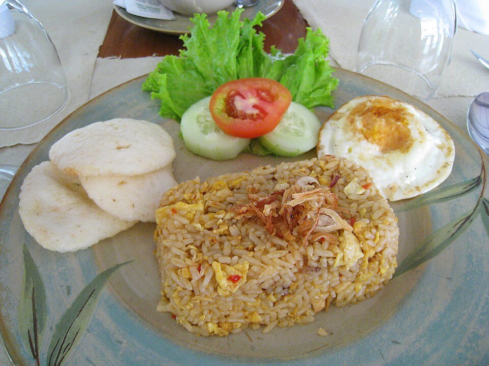 A plate of nasi goreng with egg and crackers