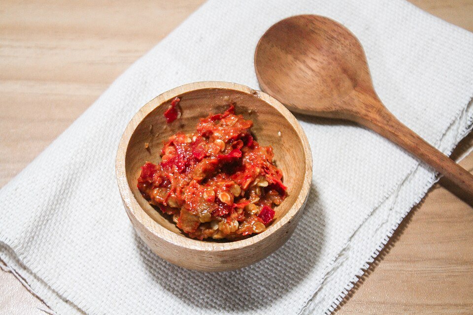Chunky red sambal with a wooden spoon